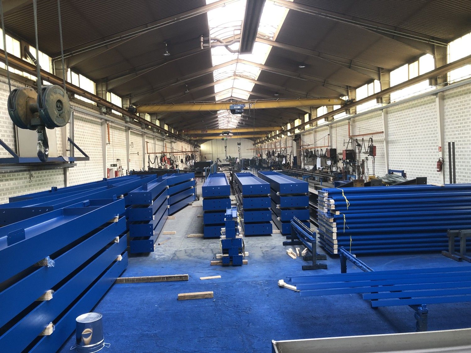 Metallbauteil in Industriehalle auf Traversen liegend mit Korrosionsschutzüberzug, im Hintergrund Teile und Hallenausstattung.